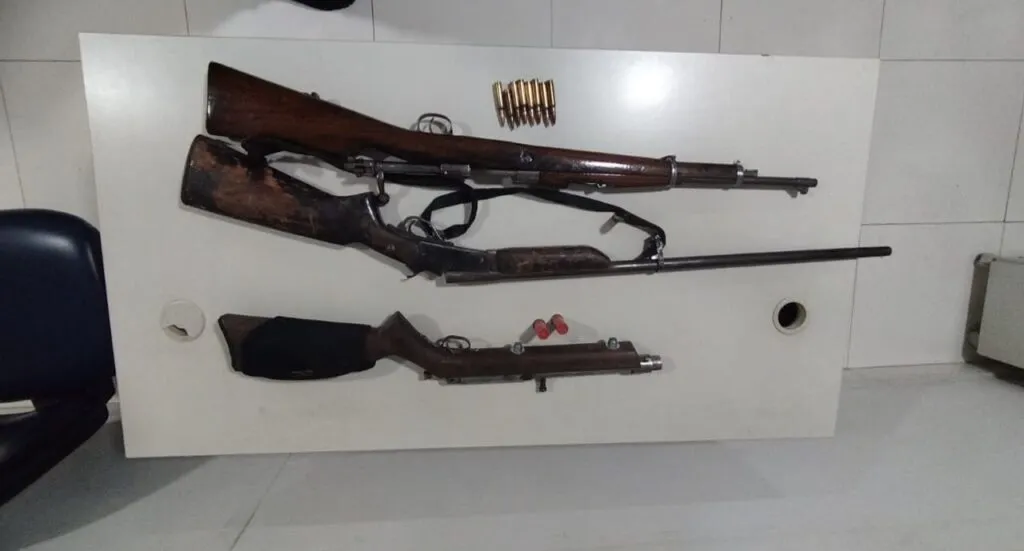 Armas longas e munições dispostas sobre uma mesa após apreensão